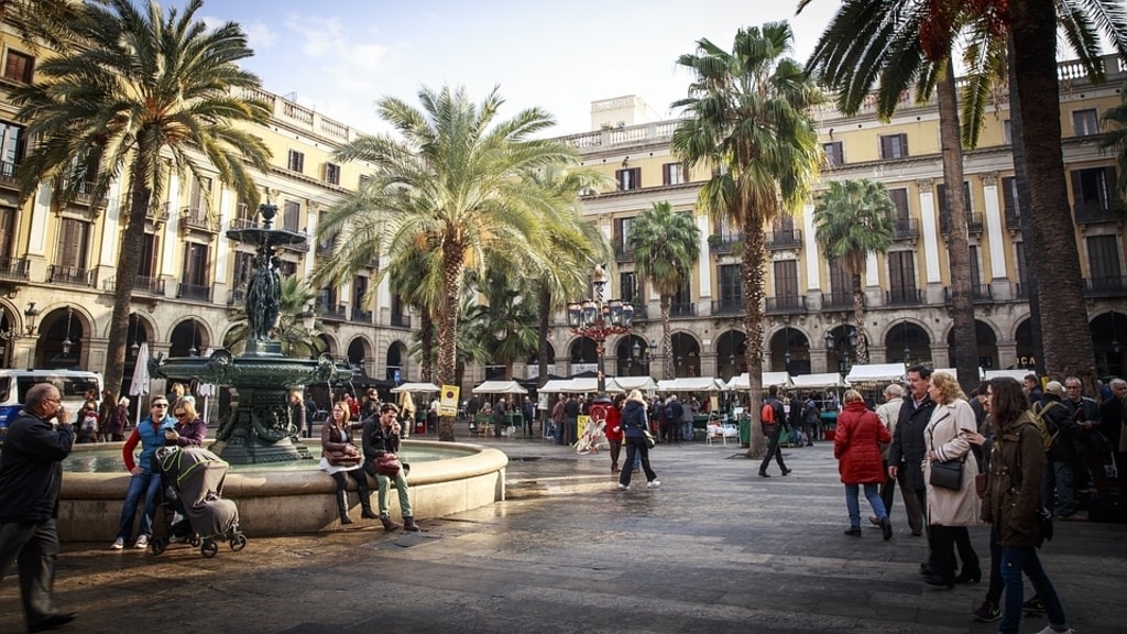 Barcelona city square people walking palm trees