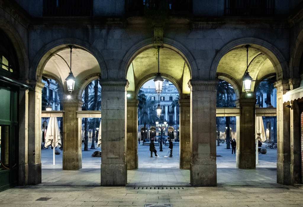 Three big arches in a building with people walking behind.