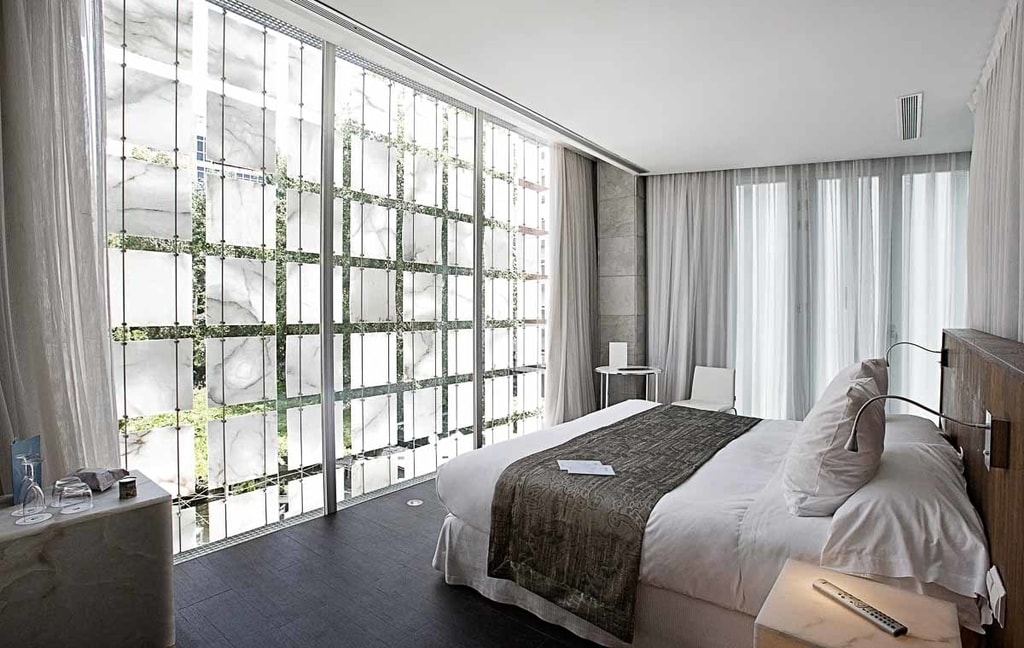 Bed in room with large windows in Hospes Palacio de los Patos