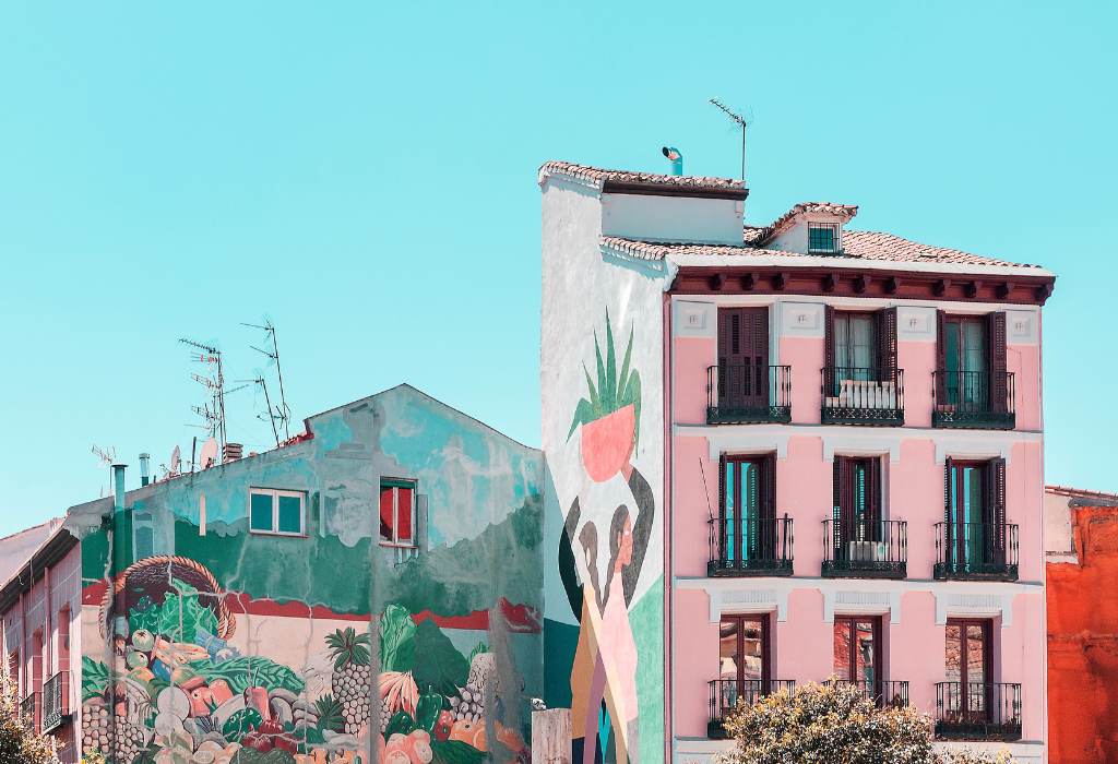 Pink block of flats with large colorful wall mural.