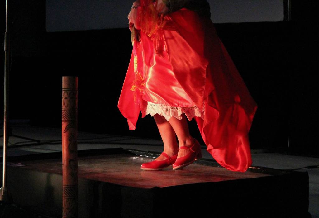 Dancer in a red dress on black stage.