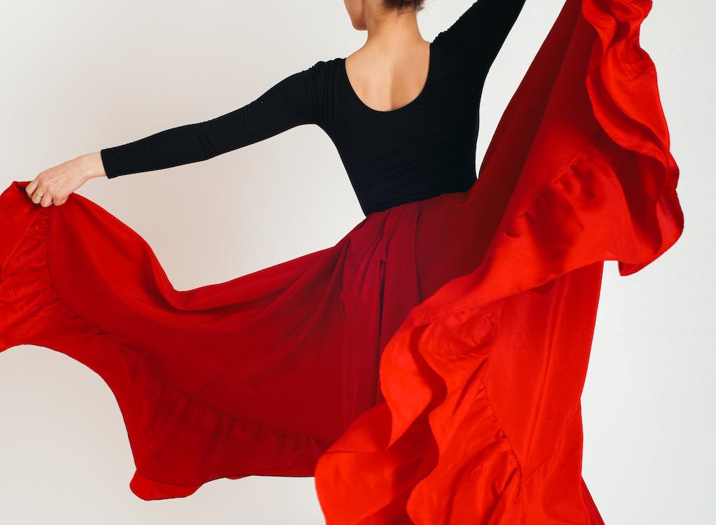 Image of a twirling flamenco dancer in bright red dress and black top.
