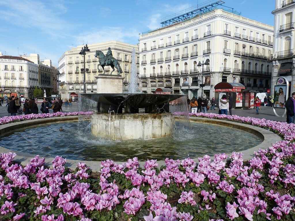 purple-flowers-around-fountain-with-statue-in-madrid