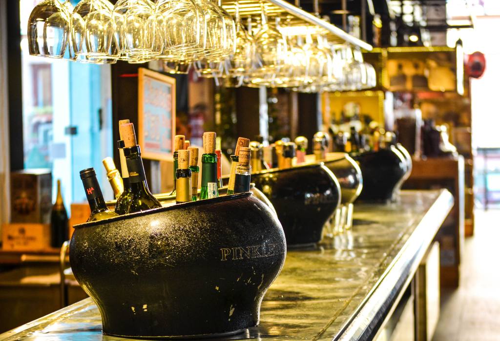 Wine glasses and wine in ice buckets at the bar.