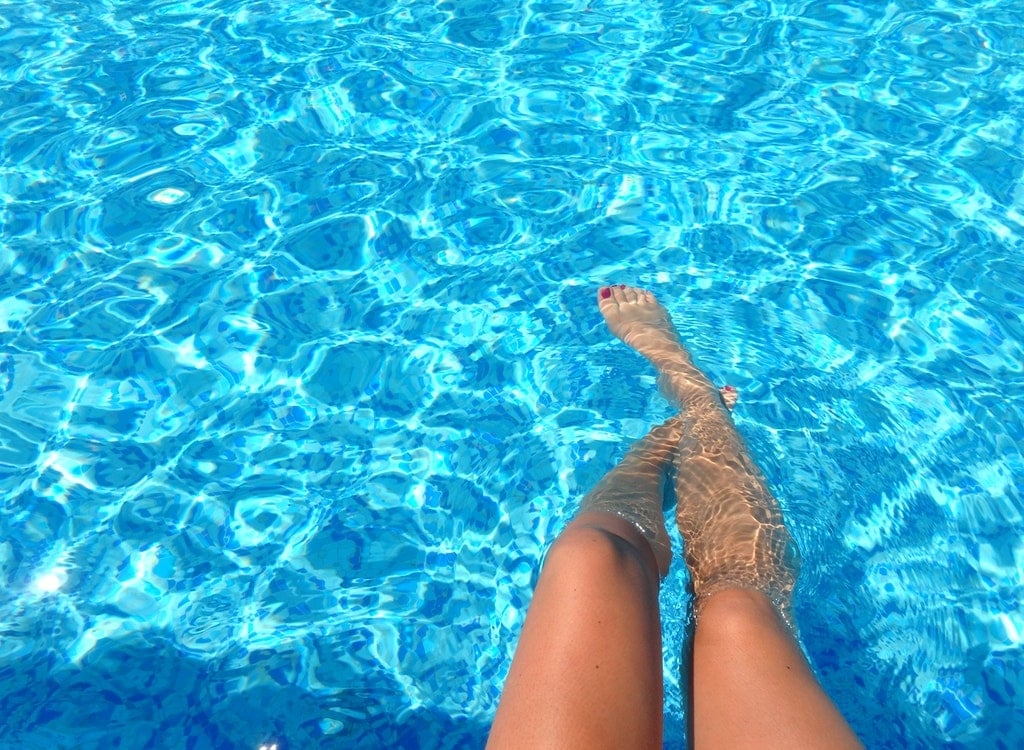 Image of a lady relaxing her legs in the pool.