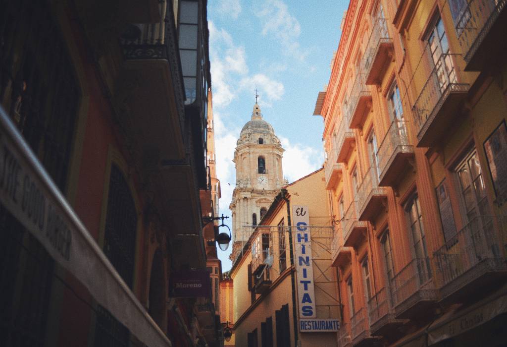 An alleyway in Malaga with a view of a church and a hotel.
