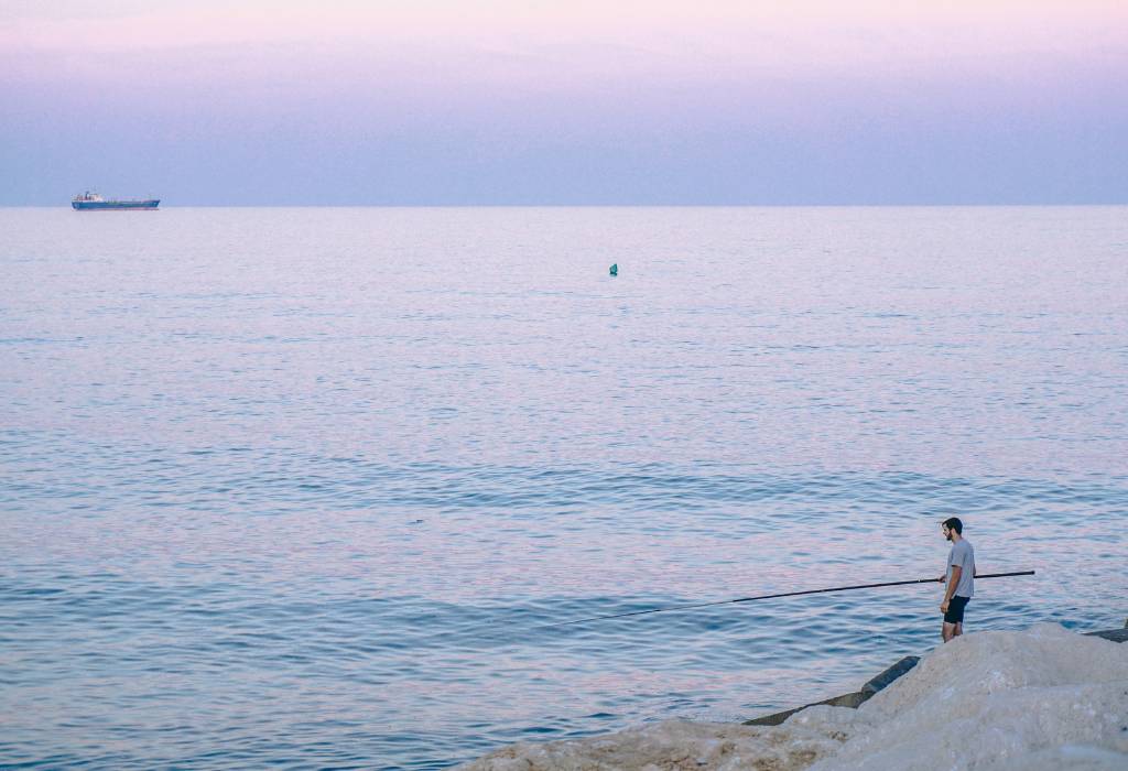 Man standing with fishing rod at dusk.