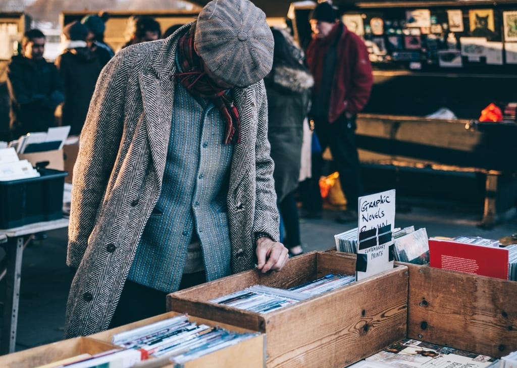 Person at a flea market browsing through second-hand goods
