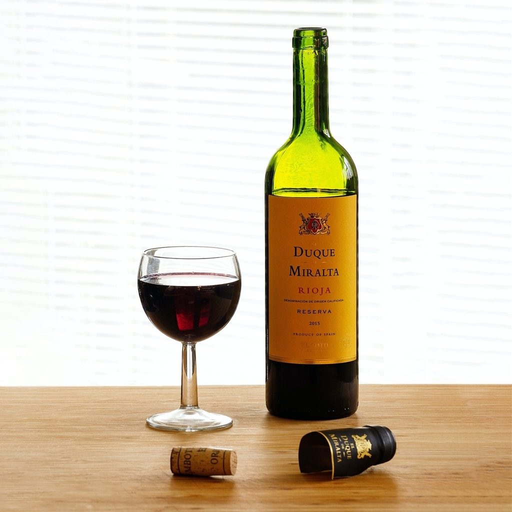 opened-bottle-of-rioja-red- duque-miralta-with-a-glass-of-wine-standing-next-to-it