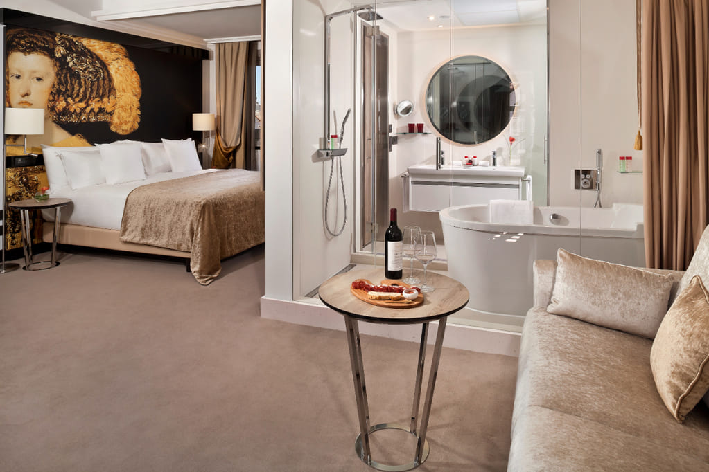 Hotel room of Palacio de los Duques in Spain with white and brown accents and bathroom