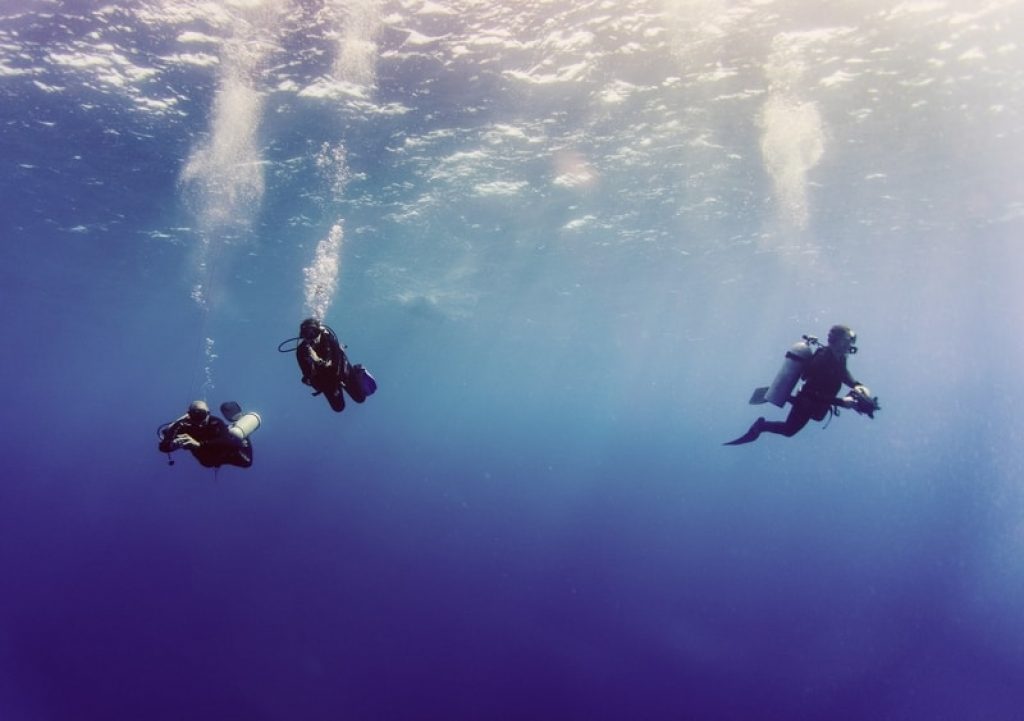 Three people scuba diving in open water