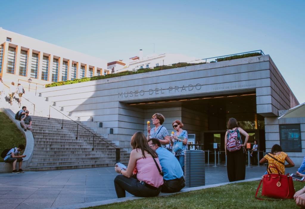 Museum entrance with people sitting in front.