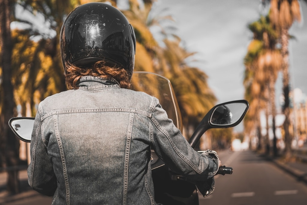 Women riding motorcycle next to palm trees